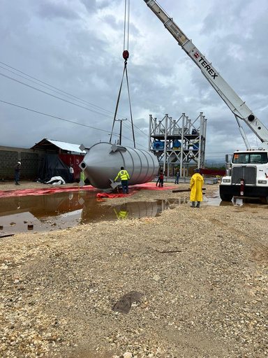 Grúa izando un tanque junto a la torre de producción en construcción