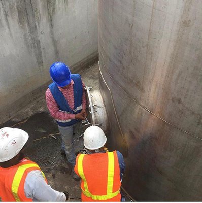 Técnicos con equipo de protección revisando el interior de un tanque